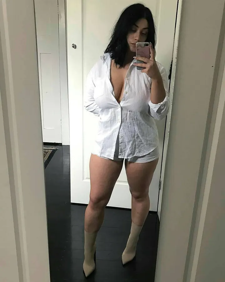 Femme en sous-vêtements noirs, prenant un selfie dans un miroir, pose détendue