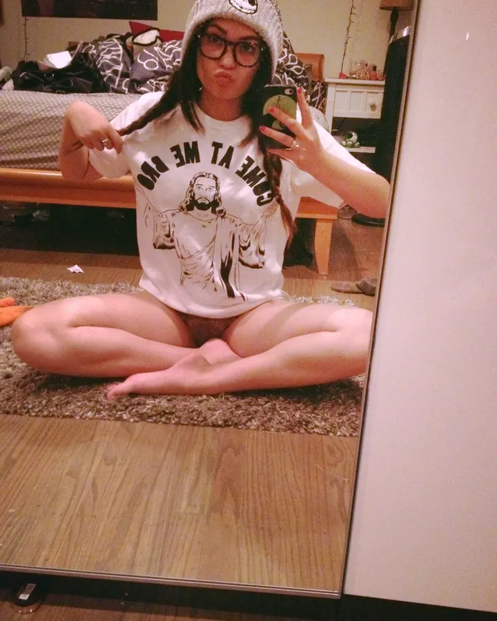 Femme en bonnet et t-shirt blanc, prenant un selfie dans un miroir, pose détendue